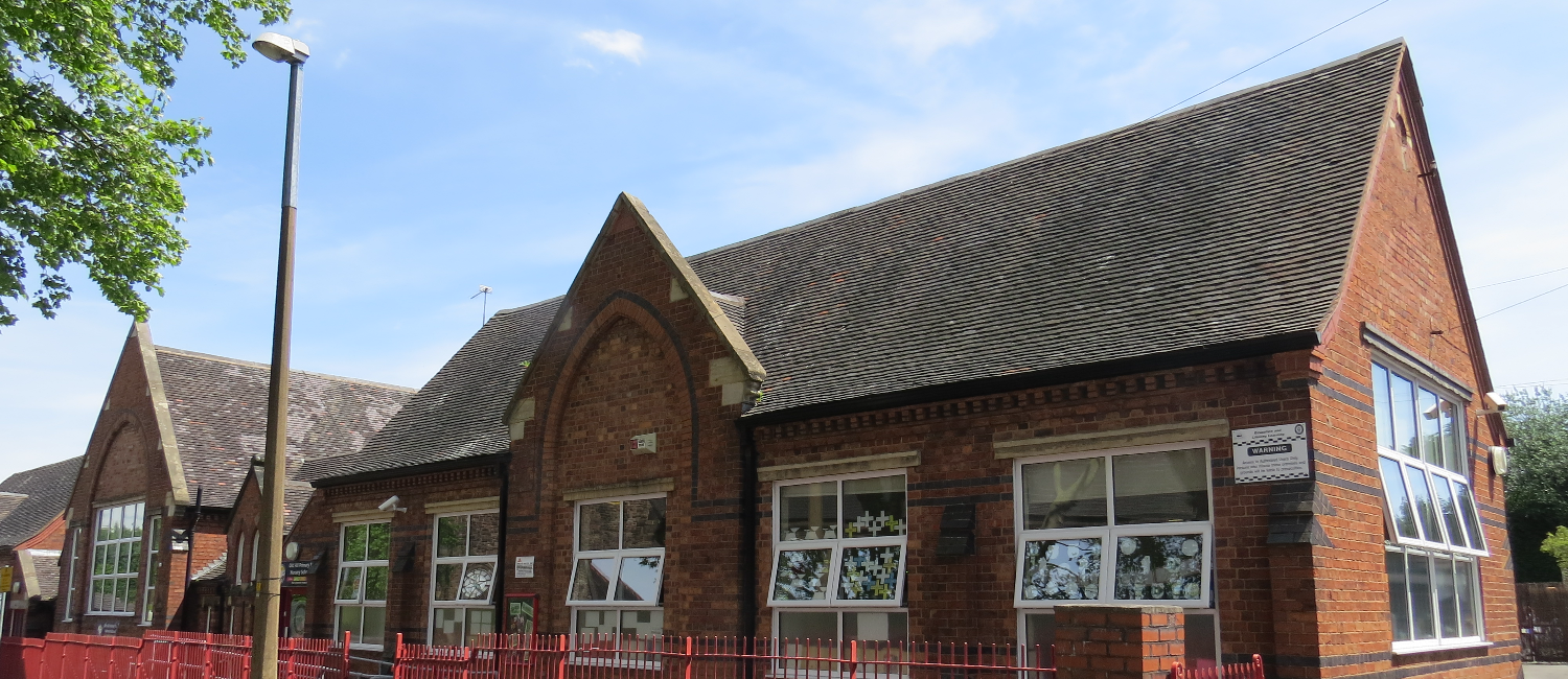 Oldbury school building, squat, with brown brick walls and a grey tiled, upside down V shaped roof.